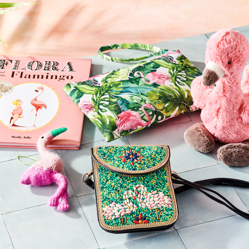 book named flora and flamingo, two flamingo print cases, and a plush flamingo