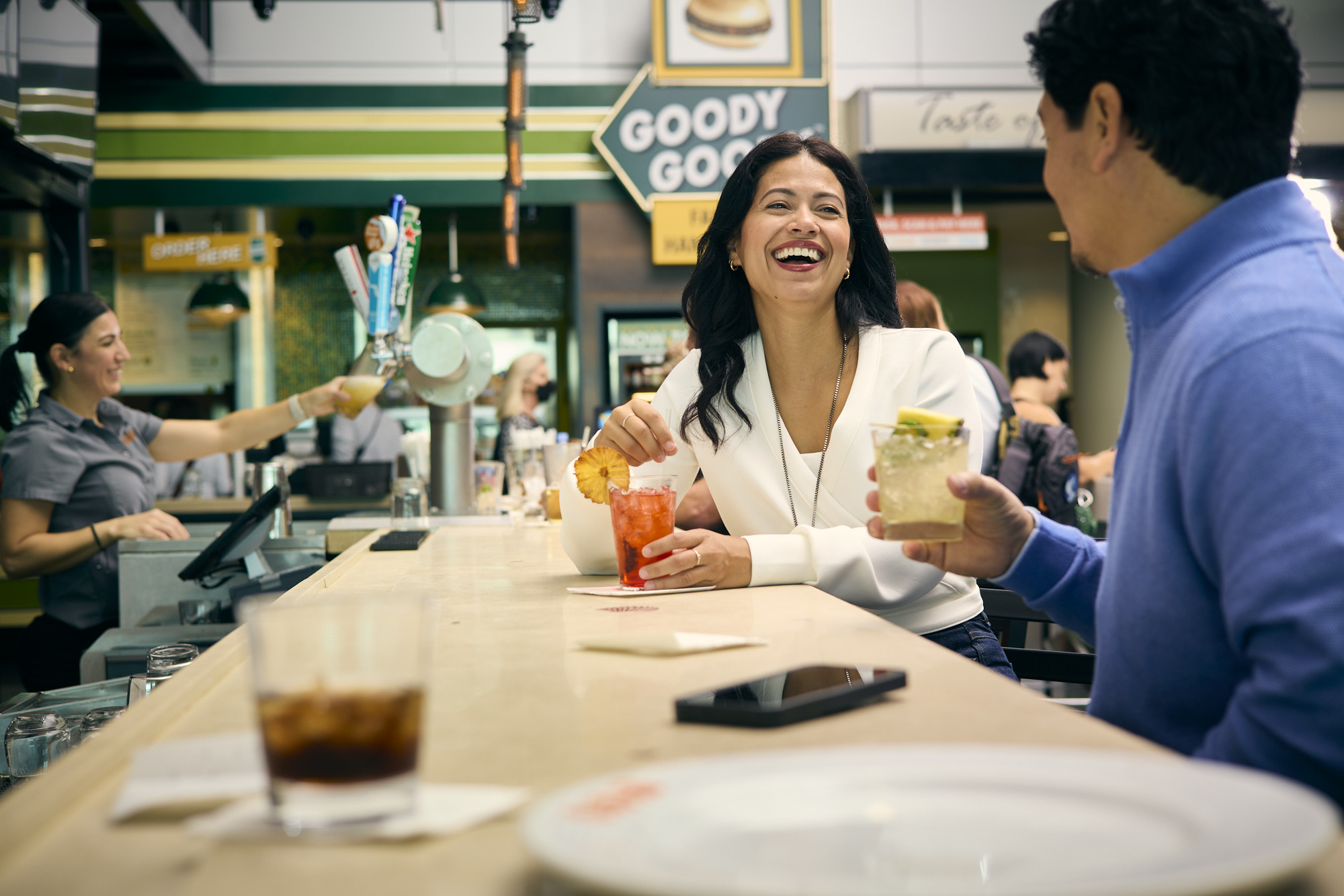 to adults having a drink at a bar with server bpour dring from a tap