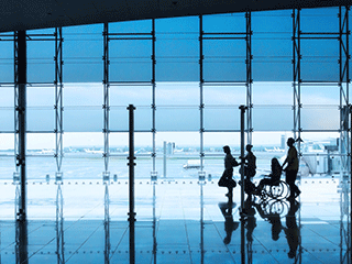 Person in wheelchair pushed by group through airport terminal