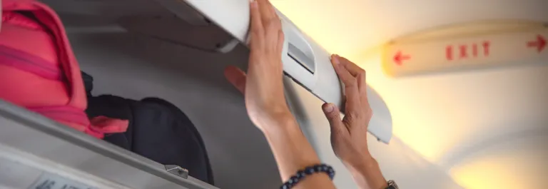 passenger closing overhead bin on airplane