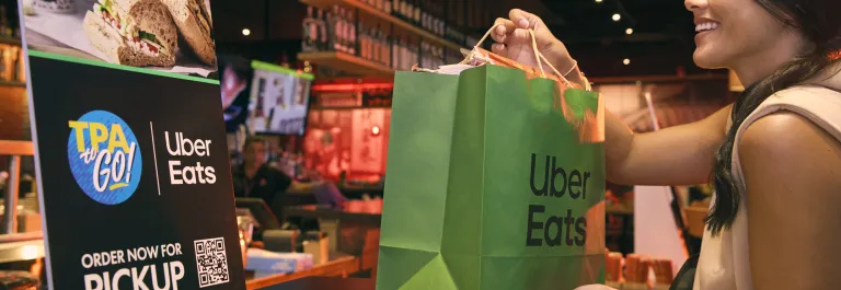 woman picking up uber eats bag