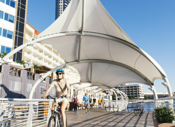 people riding bikes and walking along the Tampa Riverwalk
