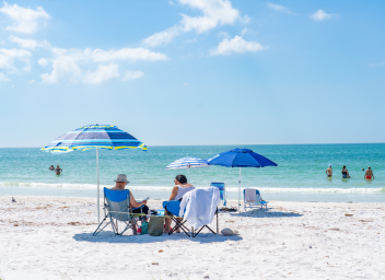 a couple in beach chairs along shoreline of white sand beach