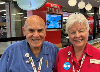 Male and female TPA ambassadors smiling in front of Welcome to Tampa Bay sign