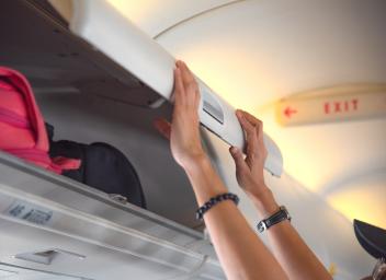 passenger closing overhead bin on airplane